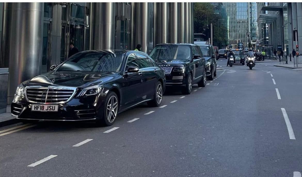 A group of luxury cars including a Mercedes-Benz S-Class, Range Rover, and V-Class parked outside an office, ready to pick up clients.